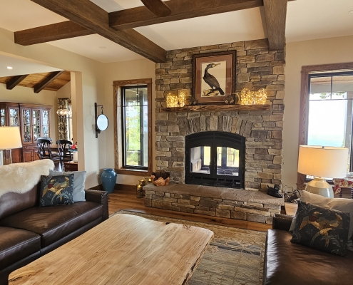 view of stone chimney in living room and fireplace that opens to porch and living room