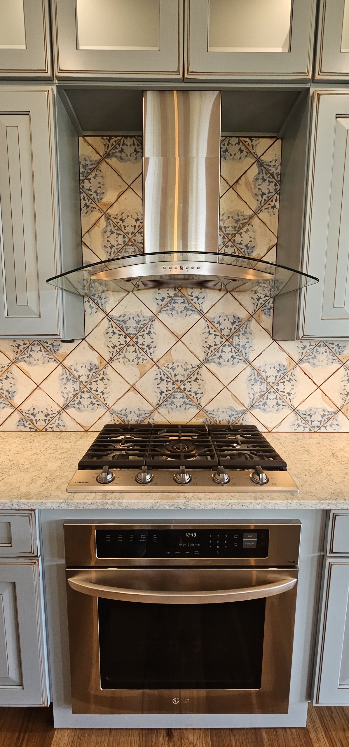 built in range with tile backsplash and range hood