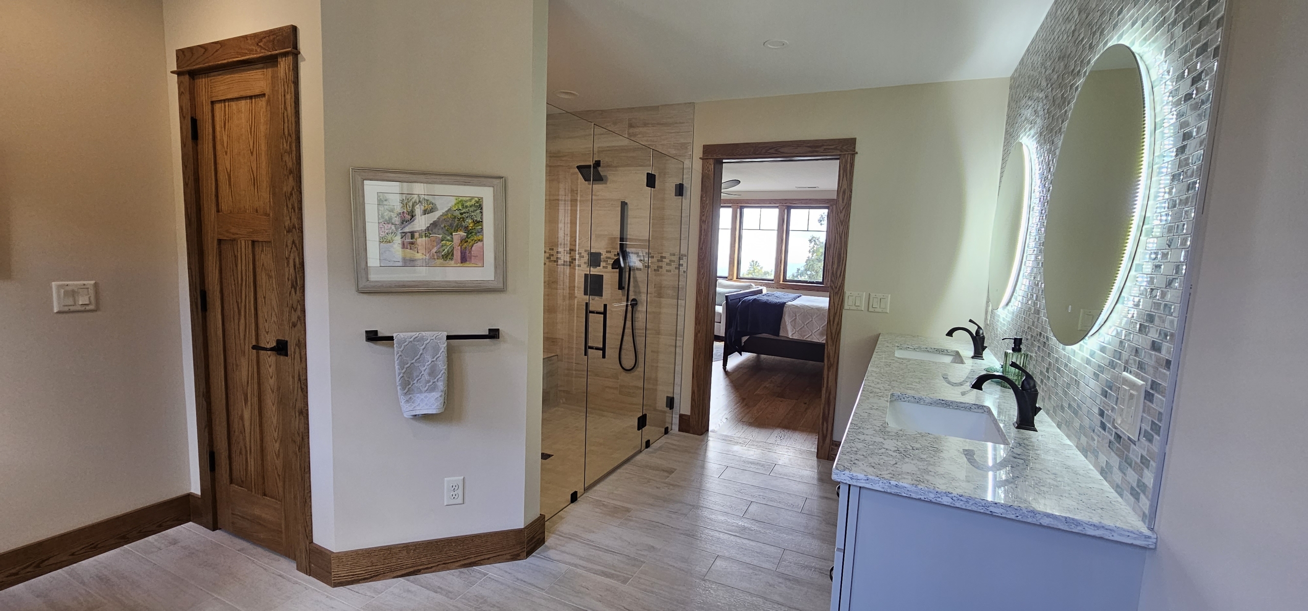 custom tile shower and vanity looking out of the bathroom door into the primary suite