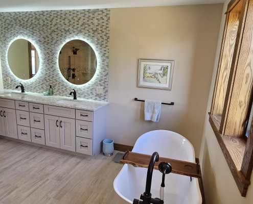 free standing bathtub with vanity and two round mirrors in the background