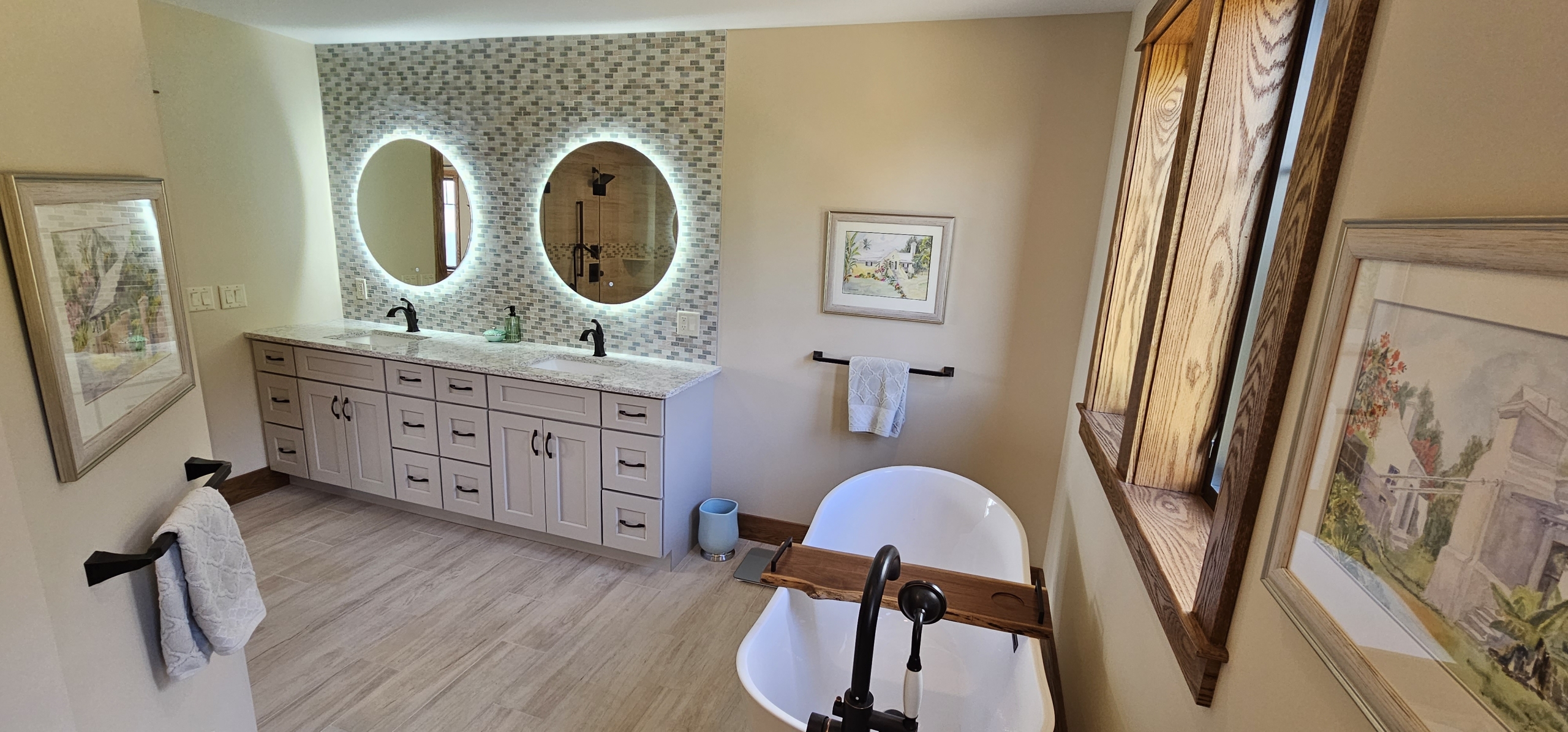 free standing bathtub with vanity and two round mirrors in the background