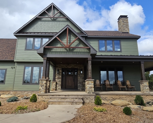 front entry to house with timber truss and green siding