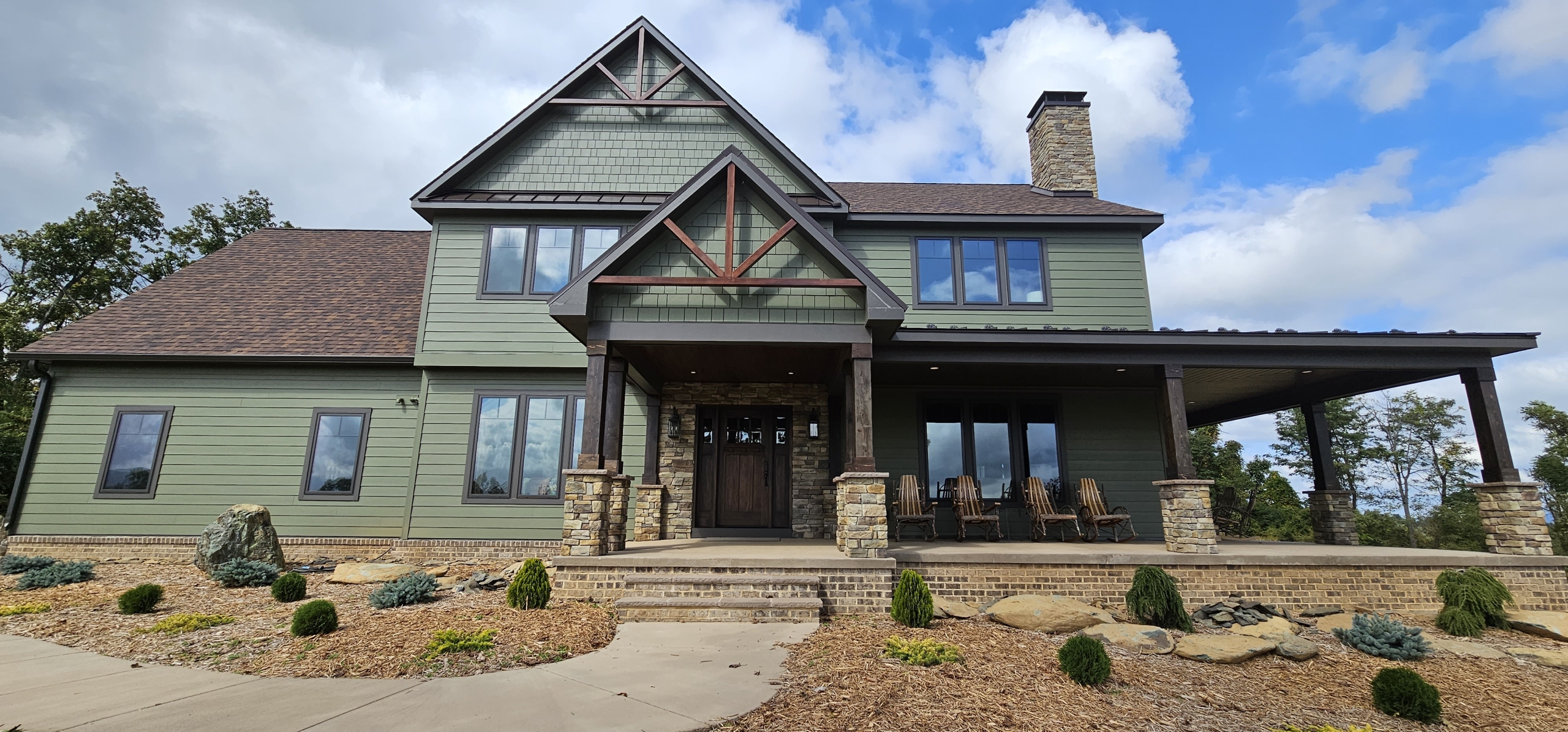 front entry to house with timber truss and green siding