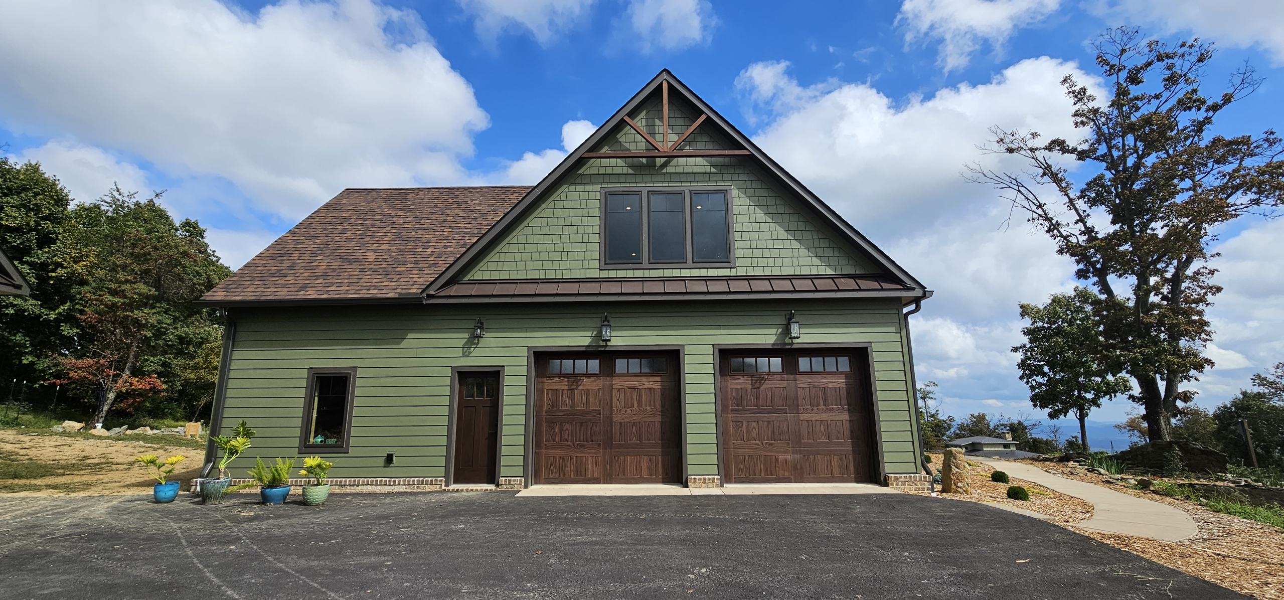 exterior garage wall showing green siding, wood garage doors and timber truss